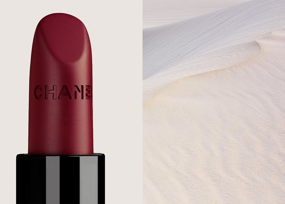 Burgundy Chanel lipstick next to a sand dune, creating a juxtaposition of beauty and nature, elegance, and stark simplicity.