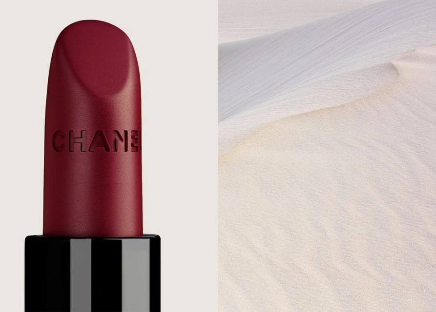 Burgundy Chanel lipstick next to a sand dune, creating a juxtaposition of beauty and nature, elegance, and stark simplicity.
