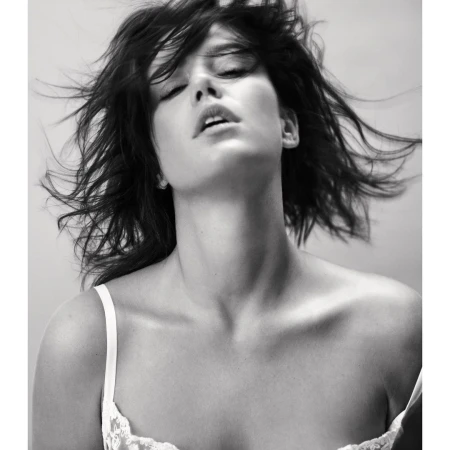 Black and white portrait of an adult woman with flowing hair. She is in lingerie with her eyes closed in an indoor setting.
