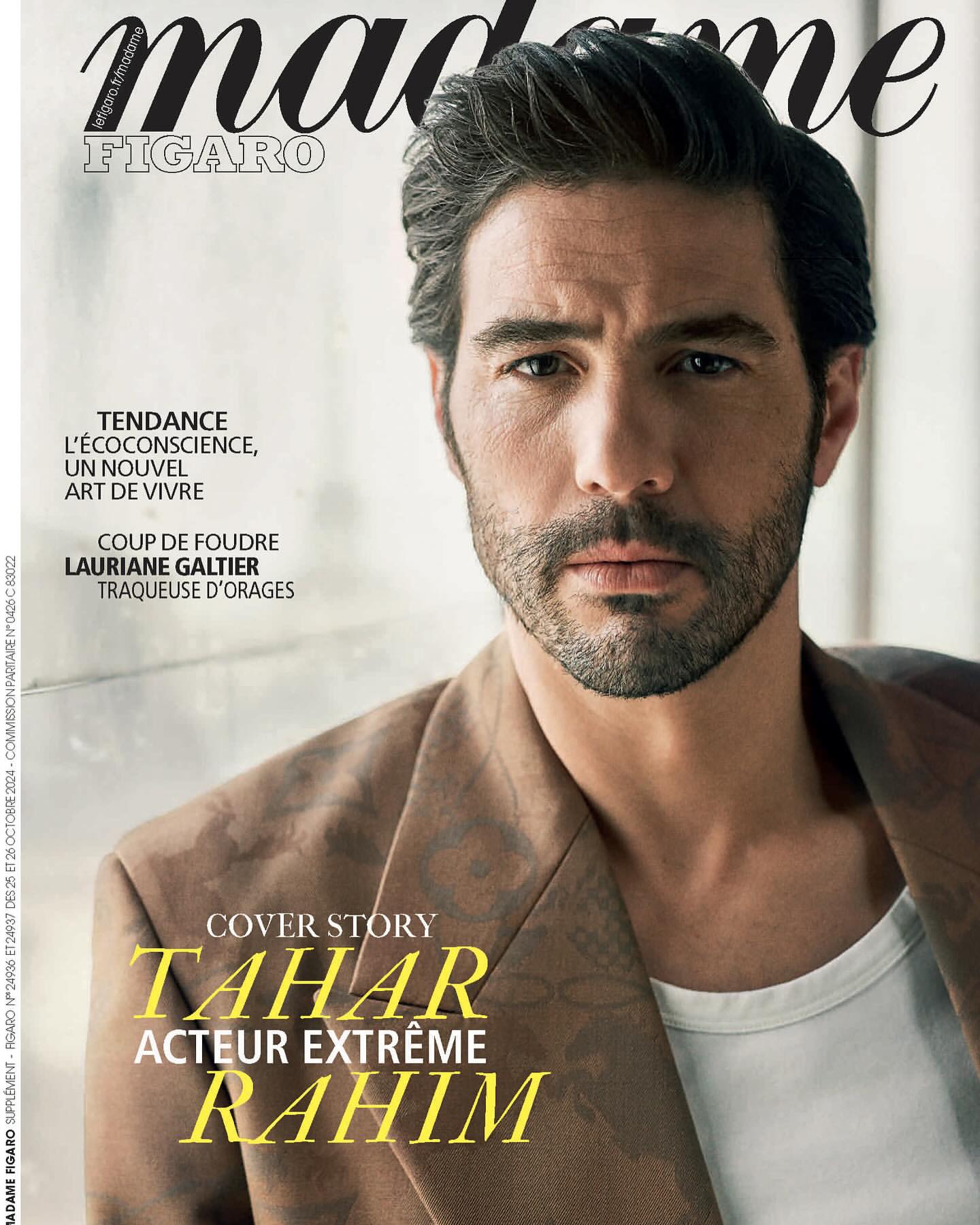 Magazine cover featuring a man with dark hair and a beard, wearing a blazer and white undershirt, posing against a blurred backdrop.