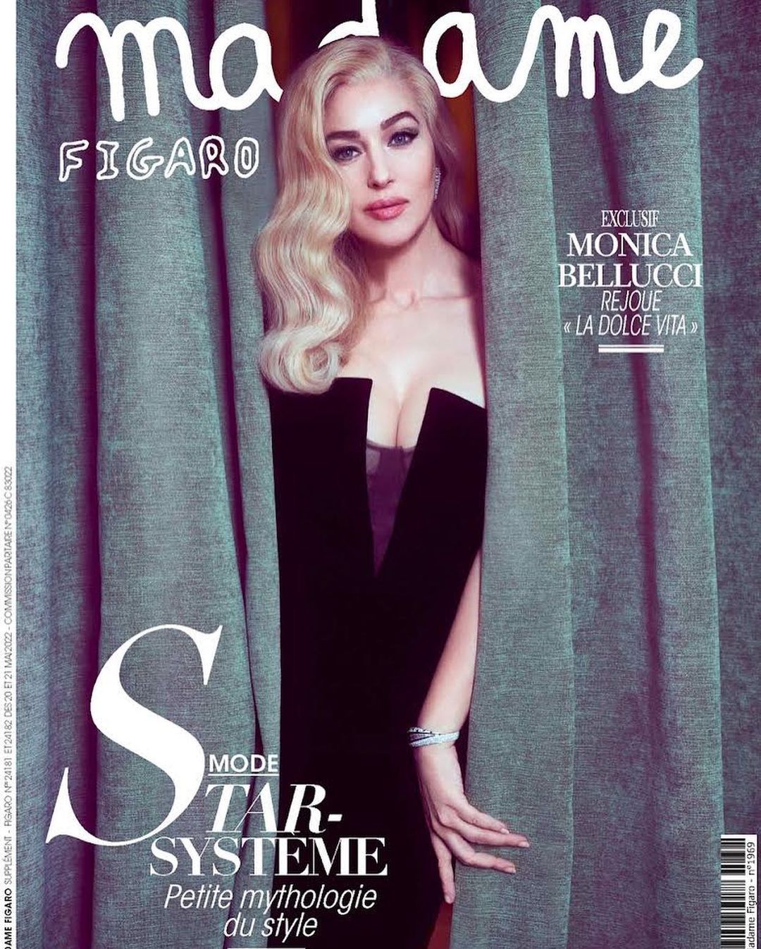 Monica Bellucci is featured on a magazine cover with blonde hair, wearing a black dress, and framed by grey curtains.