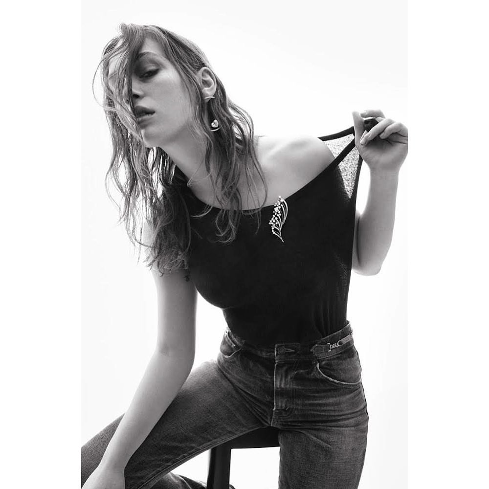 Model in black top and jeans pulling her neckline, photographed by Thiemo Sander against a bright white background