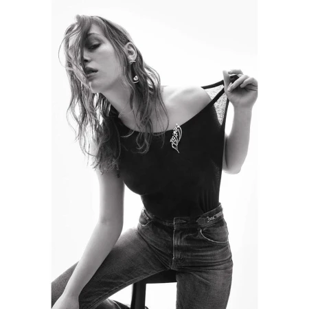 Model in black top and jeans pulling her neckline, photographed by Thiemo Sander against a bright white background