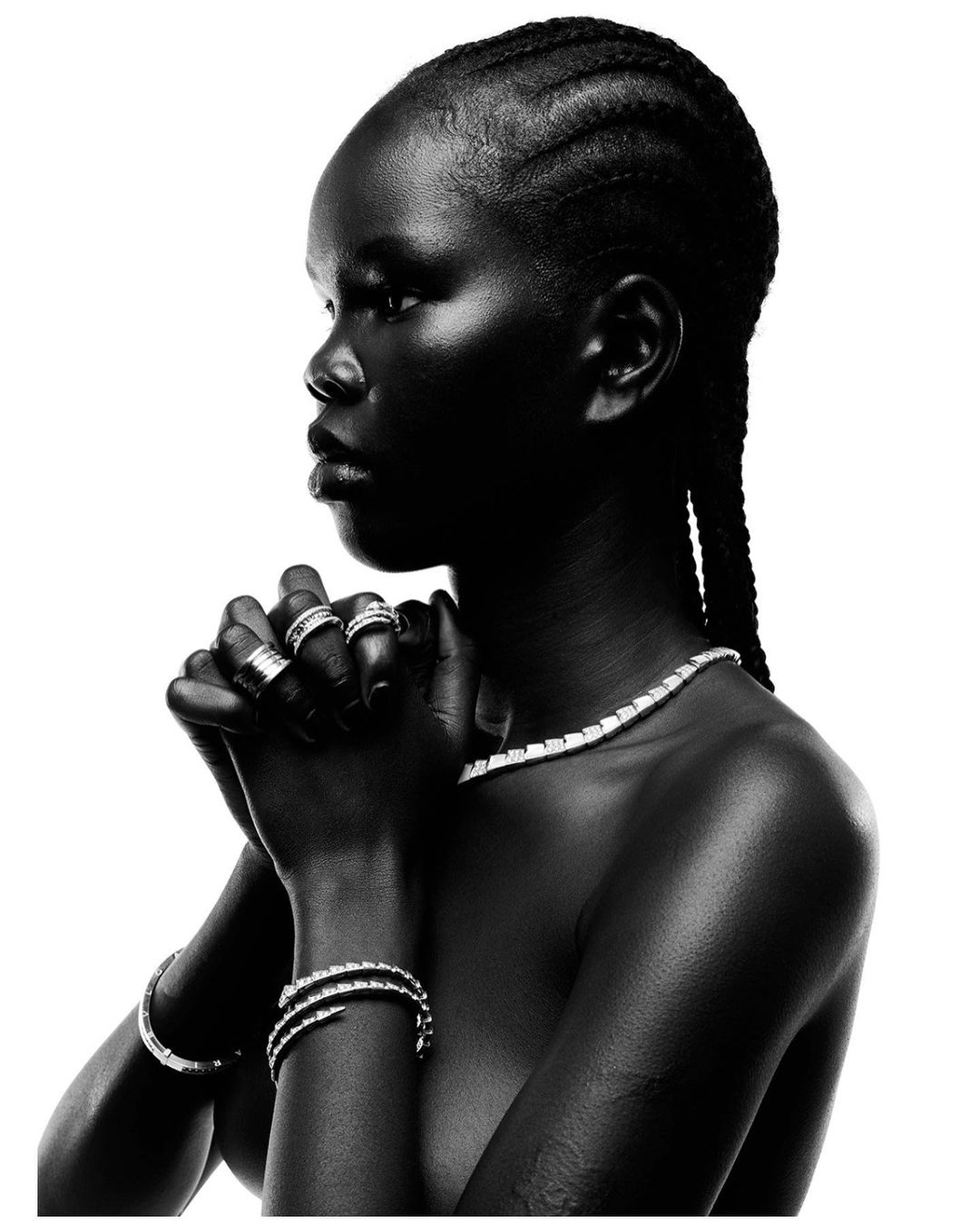 Black and white portrait of a woman with braided hair wearing diamond rings and a necklace, photographed by Thierry Le Goues.