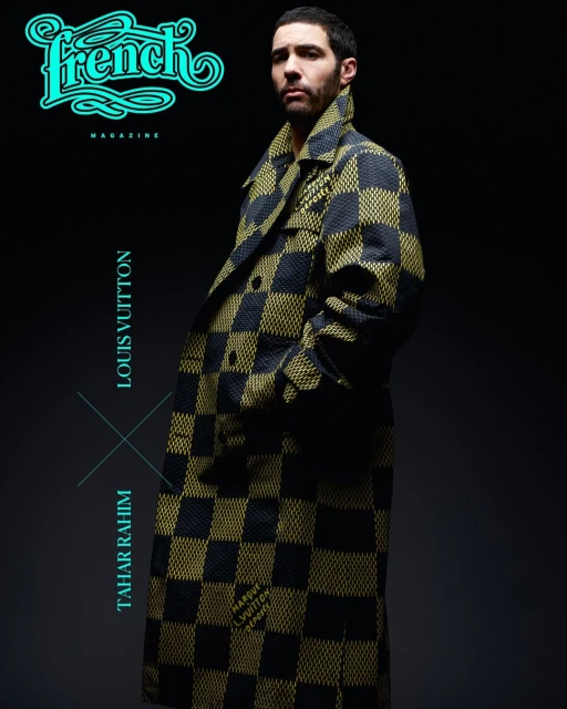 Tahar Rahim poses in a black and gold checkerboard coat, featured in French Magazine against a gradient grey background in studio lighting.
