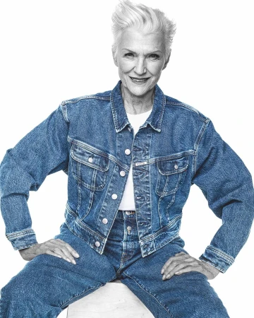 Elderly woman with white hair wearing a denim jacket and jeans against a white background