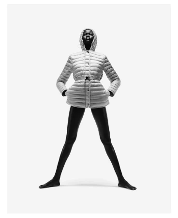 Fashion shot of an African woman wearing a white puffer jacket with a hood, standing in a wide stance against a bright white backdrop.