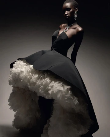 Black woman wearing a strapless black gown with voluminous white ruffled underskirt and diamond jewellery by Thierry Le Gou&egrave;s
