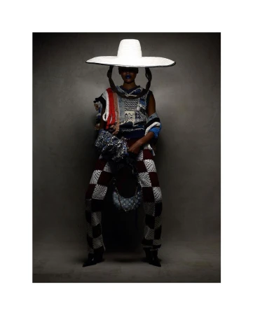 Fashionable person in checkered pants, knit top, and large hat in a studio shot, showcasing unique textures and design elements.