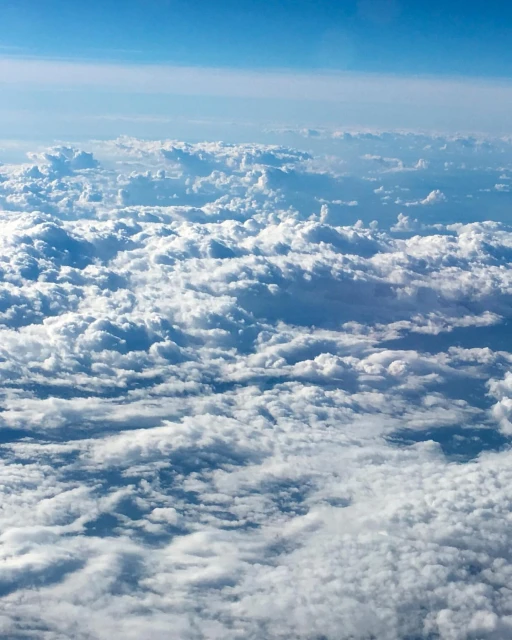 Aerial view of cumulus clouds with blue sky above, creating a serene and picturesque skyscape. High-altitude, bright, atmospheric conditions.