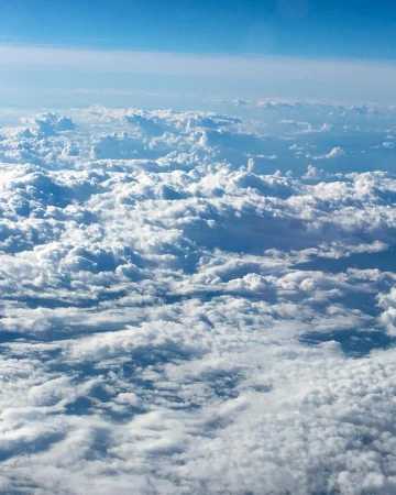 Aerial view of cumulus clouds with blue sky above, creating a serene and picturesque skyscape. High-altitude, bright, atmospheric conditions.