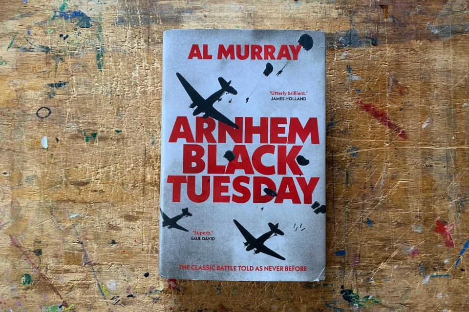 Book cover titled 'Arnhem: Black Tuesday' by Al Murray, featuring silhouetted airplanes and paratroopers against a grey sky background.