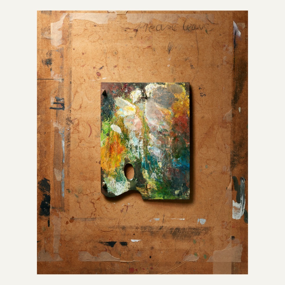 Painter's palette filled with colorful paint resting on a paint-splattered easel, creating an artistic composition.
