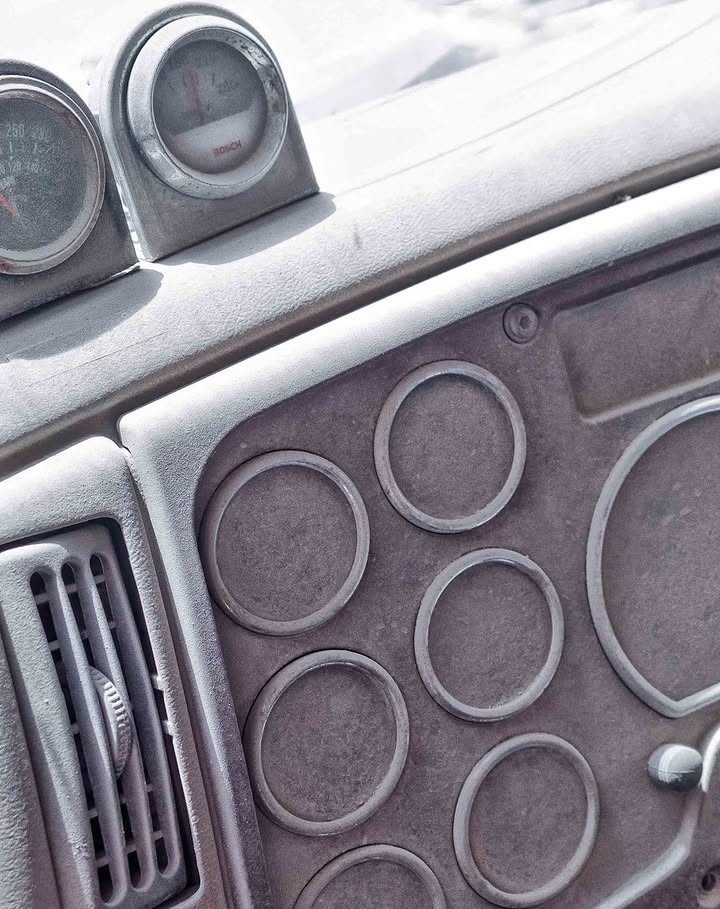 Close-up of a vehicle dashboard with gauges and air vents, featuring a textured, neutral-toned surface and circular design elements.