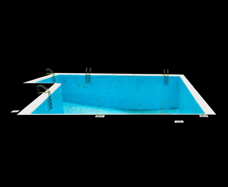 Wide shot of an empty, blue swimming pool with metal ladders on a black background, presenting an isolated and graphic composition.