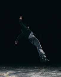 Man mid-air jumping outdoors at night wearing a dark jacket, light t-shirt, and jeans captured in Chicago by Thomas Chadwick.