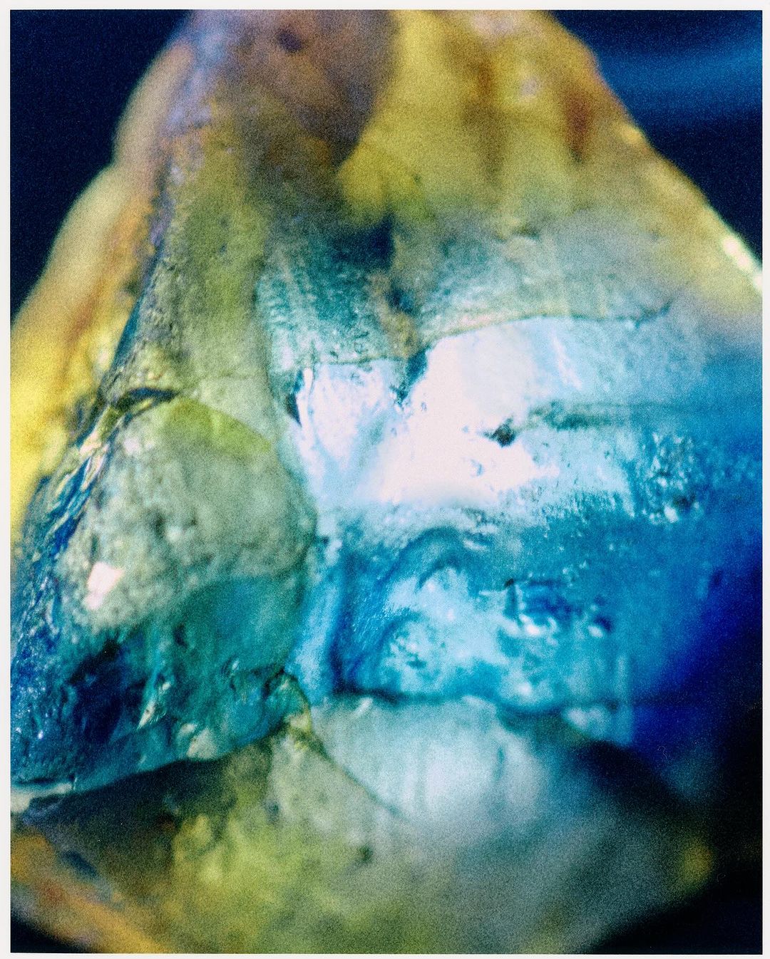Abstract image featuring blue and yellow hues, with a textured surface and light reflections, creating an ethereal and artistic aesthetic.
