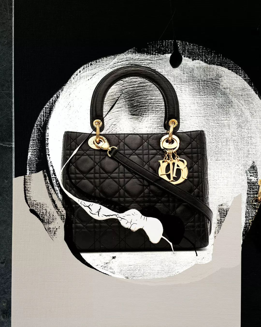 Fashion still life of a black quilted handbag with gold hardware on an abstract black and silver background.