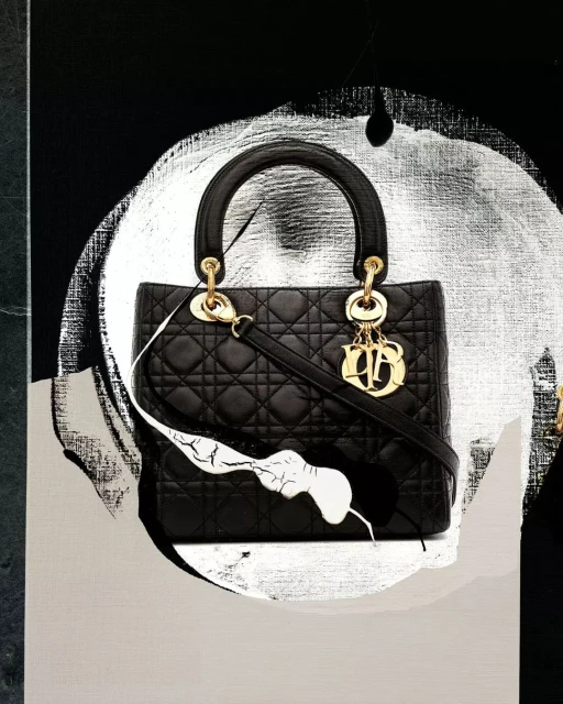 Fashion still life of a black quilted handbag with gold hardware on an abstract black and silver background.