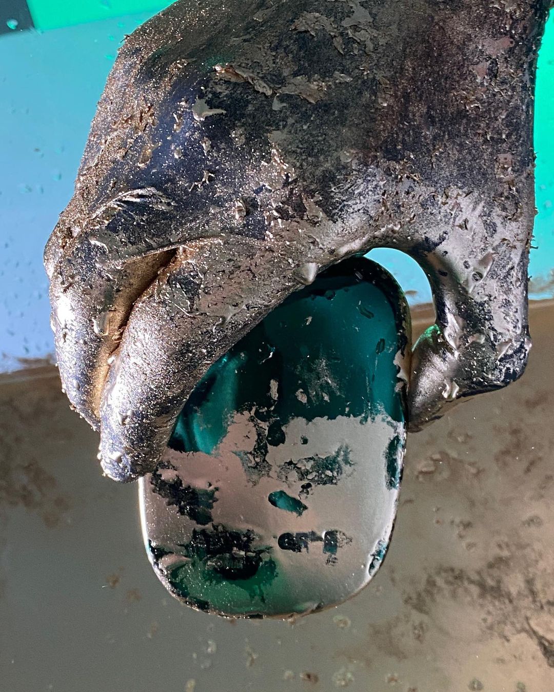 Close-up of a textured hand holding a shiny green stone, showcasing the contrast between the rough hand and the smooth polished stone.