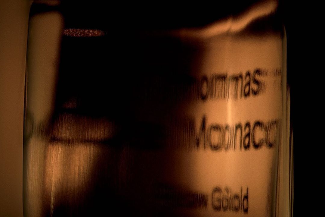 Close-up of a glass container with text on a dark background, featuring shades of brown and gold.