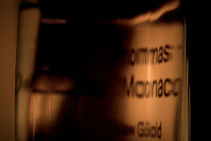 Close-up of a glass container with text on a dark background, featuring shades of brown and gold.