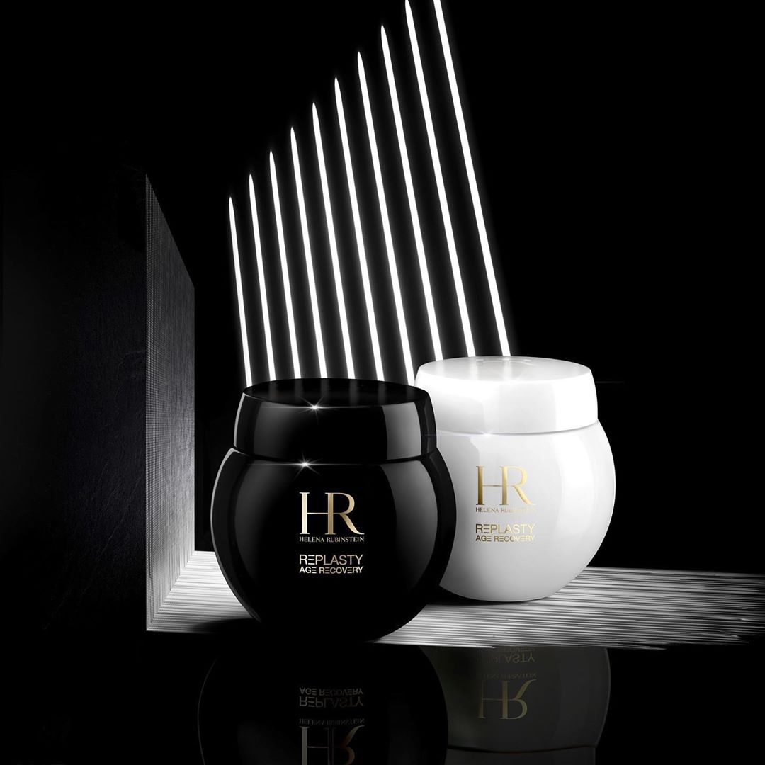 Two jars of Helena Rubinstein Re-Plasty Age Recovery skincare products, one black and one white, on a reflective surface.
