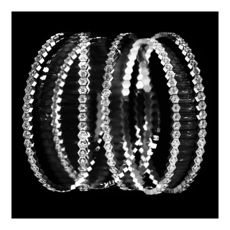 Diamond-set hexagonal link bracelets arranged in a curved layered cylinder against a solid black background.