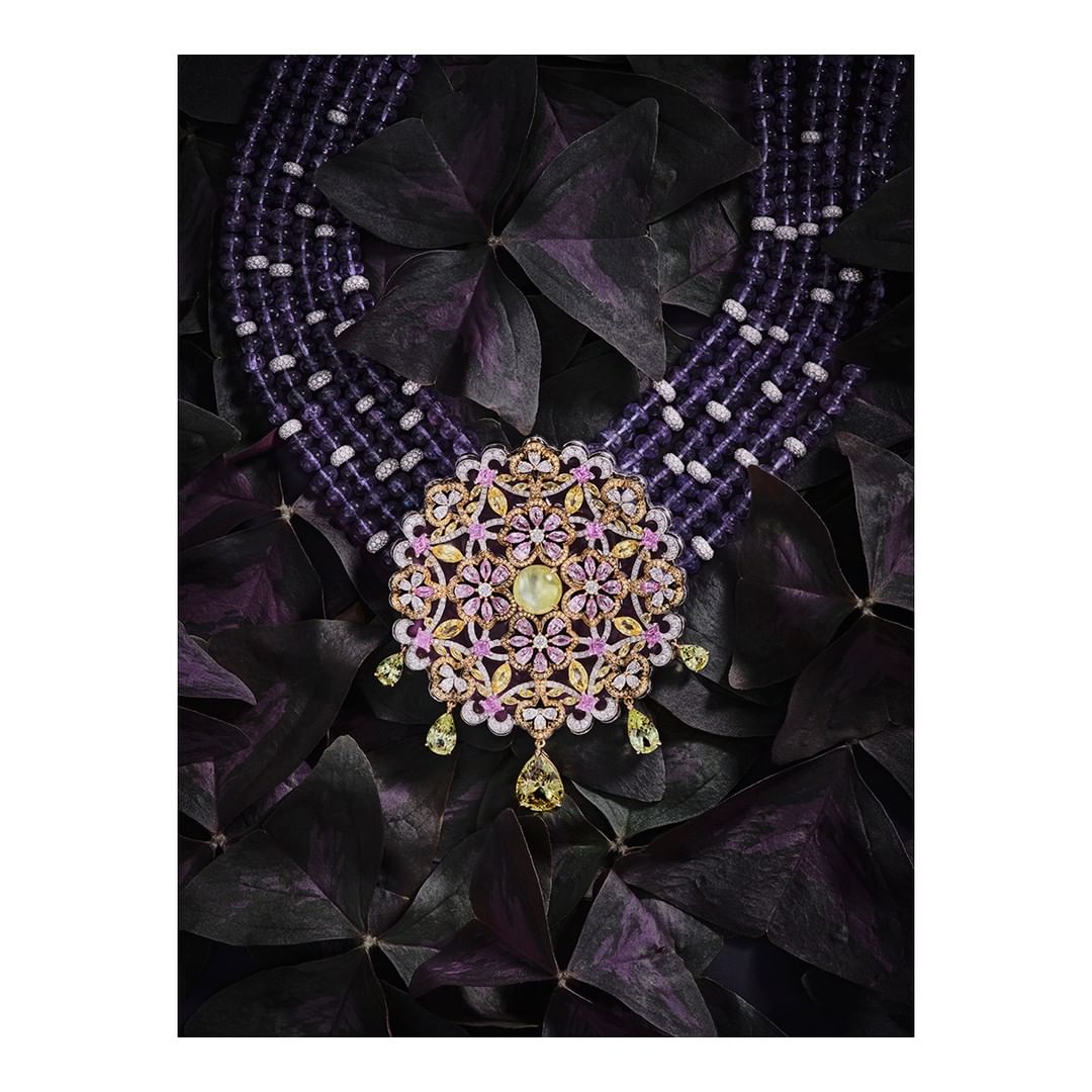 Ornate floral necklace with purple bead strands on a dark floral background. Jewelry photography for fashion and luxury advertising.