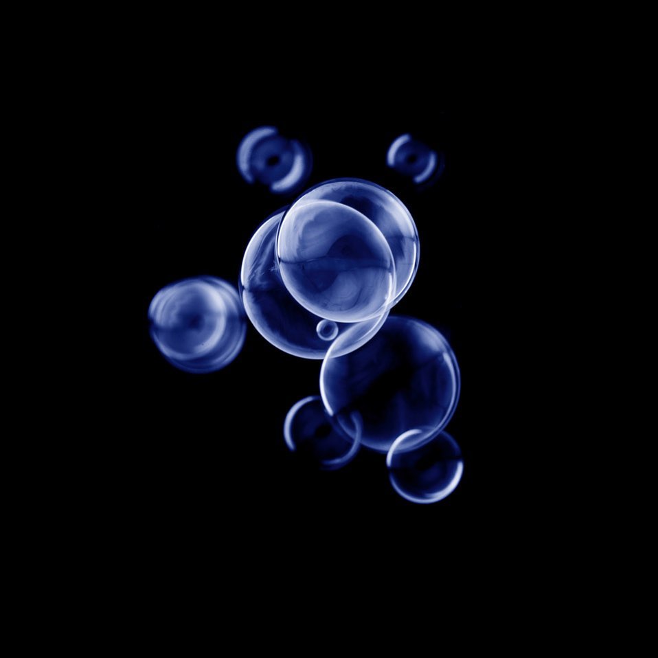 Abstract photograph of blue transparent spheres clustered against a solid black background. Artistic and modern visual element.