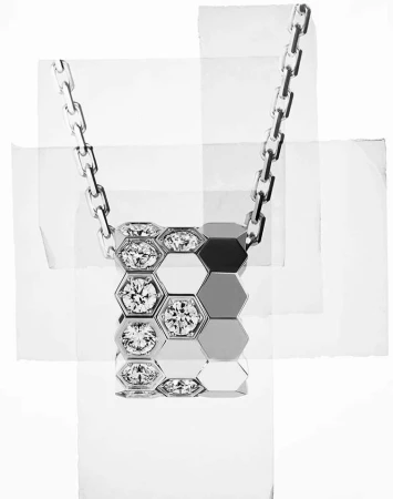 Silver necklace with a hexagonal pendant featuring diamond accents, displayed against an abstract background of white paper fragments.