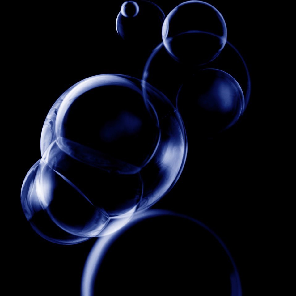 Abstract shot of translucent blue spheres floating on a black background, creating a mesmerizing and modern visual effect.
