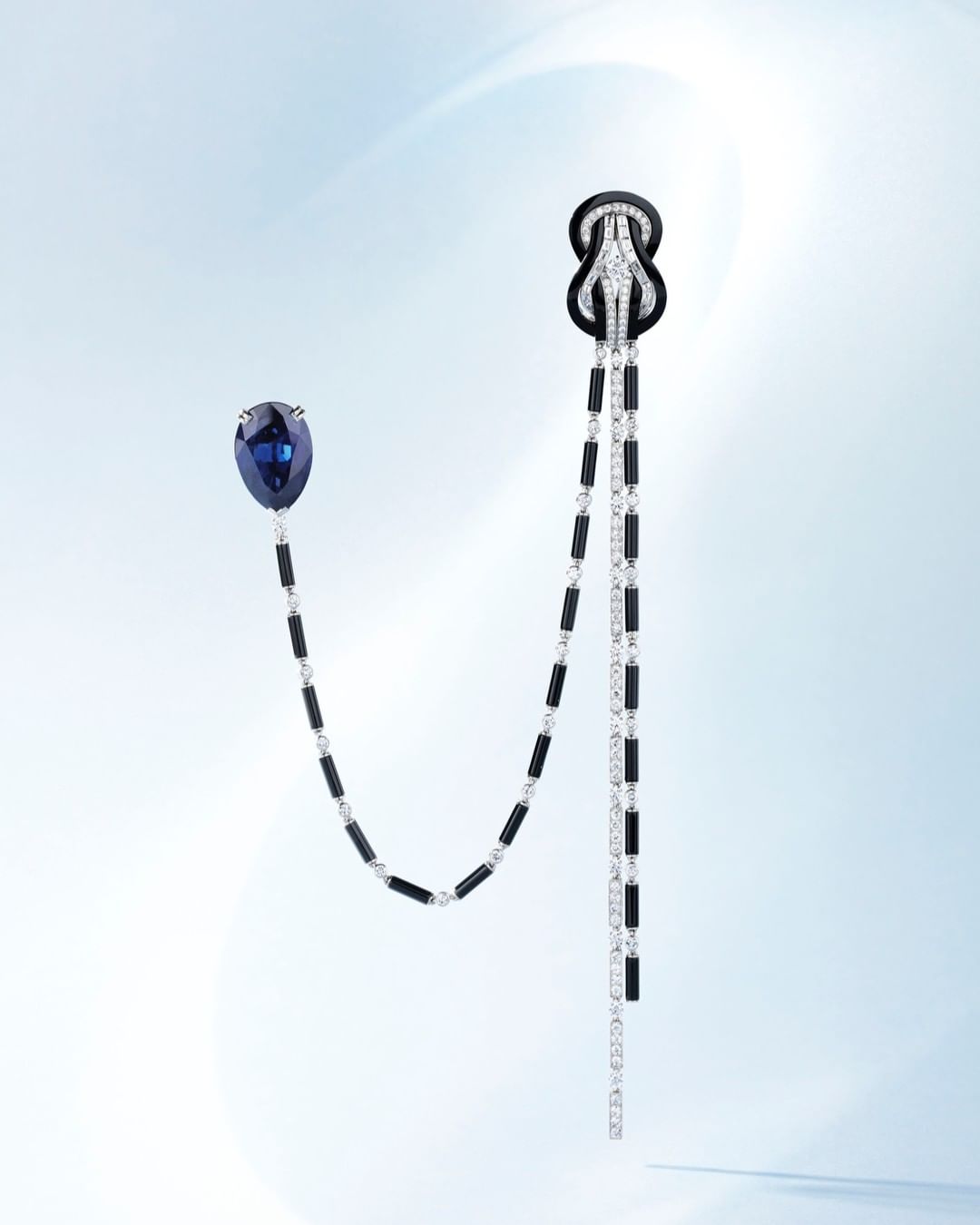 Elegant jewellery featuring blue and black gemstones with diamond accents, displayed on a soft gradient background. Sophisticated design.