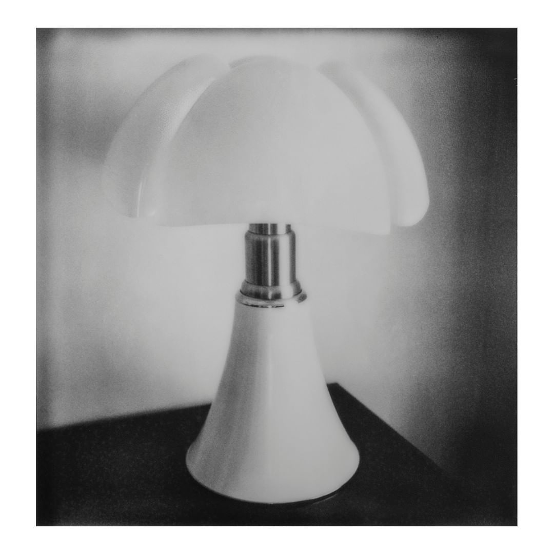 Monochromatic image of a vintage-style table lamp with a tulip-shaped lampshade, casting soft light in an indoor setting.