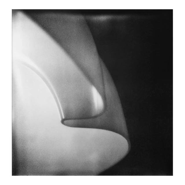 Abstract black and white photograph of light reflecting off curved surface, creating soft gradients and textured appearance.