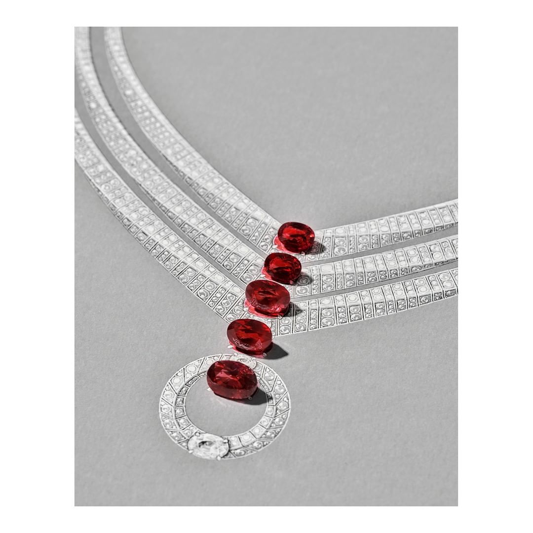 Close-up studio shot of a diamond necklace with red gemstones on a gray surface. Jewelry advertisement for the fashion industry.