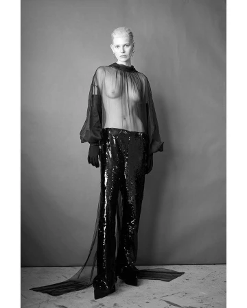 Black and white fashion shot featuring a slender adult female with fair skin, silver hair, and dramatic dark, shimmering pants.