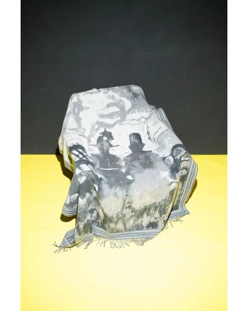 Printed scarf draped over an unseen object, featuring figures in a black-and-white vintage style, set against a yellow and black background.