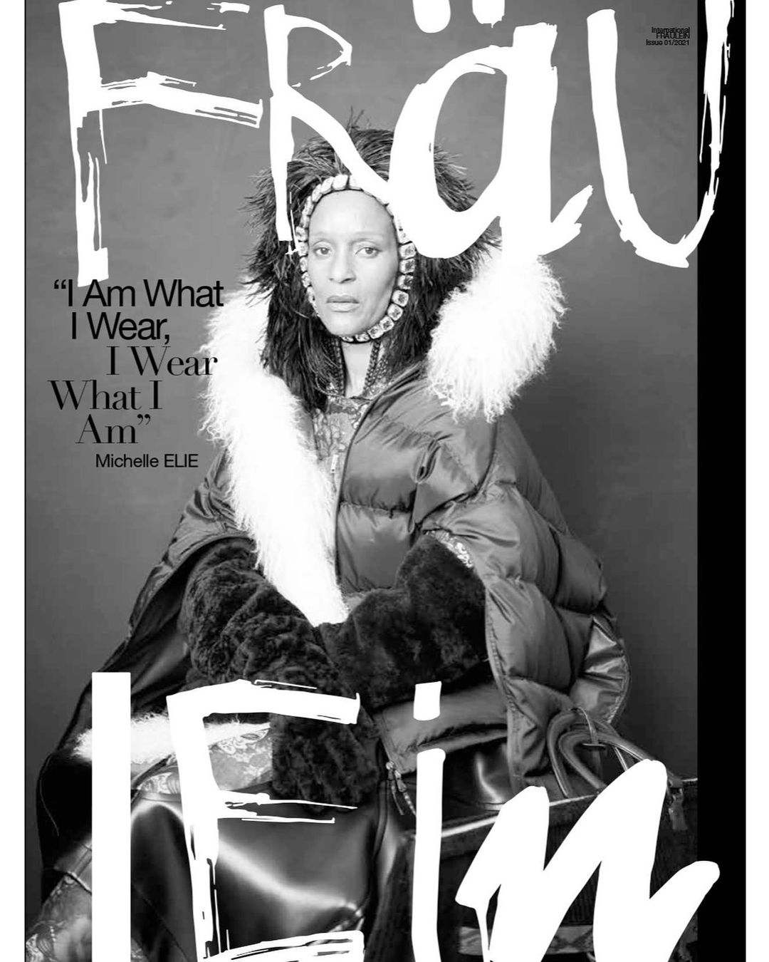 Magazine cover featuring a woman in a fur-trimmed coat and feathered headpiece against a grey background, with bold white magazine text.