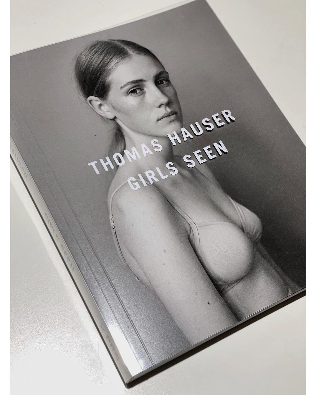 Book cover featuring a portrait of a woman with light skin wearing a bra top against a gray background, with the title 'Thomas Hauser'.