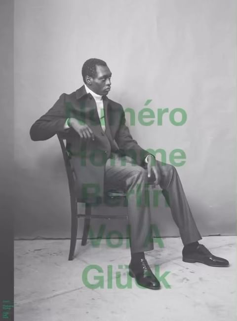 Black man in dark suit seated on a wooden chair against a plain backdrop with green overlay text by Thomas Hauser