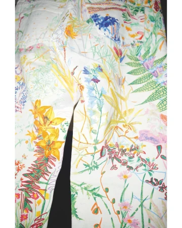 White jeans with a colorful floral pattern of yellow, blue, pink, and green flowers and foliage, creating a vibrant and artistic design.