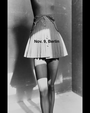 Black and white fashion shot: pleated skirt on a mannequin with fishnet stockings, in a studio with dramatic lighting.
