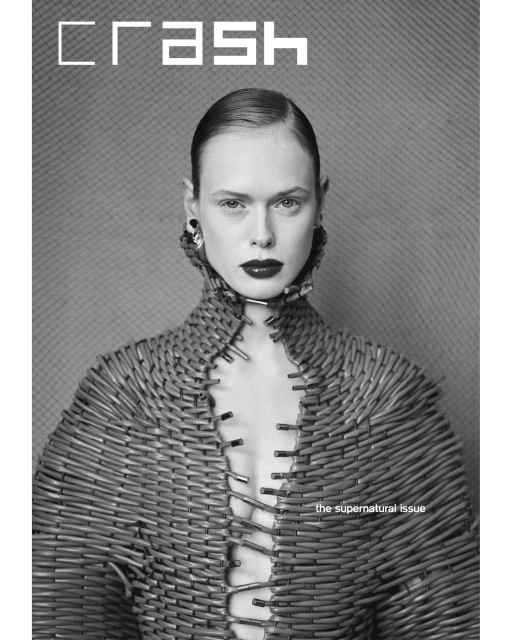 Monochrome portrait of a model wearing a textured wicker garment, silver earrings, and dark lipstick, posing for a 'Crash' magazine cover.