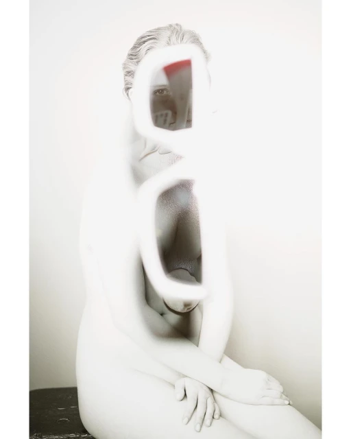 Abstract nude art photography featuring a woman with an obscured face in a blurred, desaturated style against a plain background.