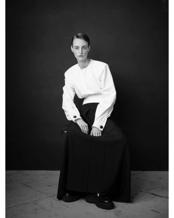 Portrait of a seated model wearing a white top and dark long skirt photographed by Thomas Hauser in Paris
