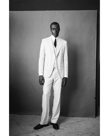 Black man wearing a pinstripe suit and tie standing against a studio backdrop, photographed in Paris by Thomas Hauser
