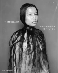 Black and white portrait of a person with long dark hair wrapped tightly around their neck like a collar, by Thomas Hauser.