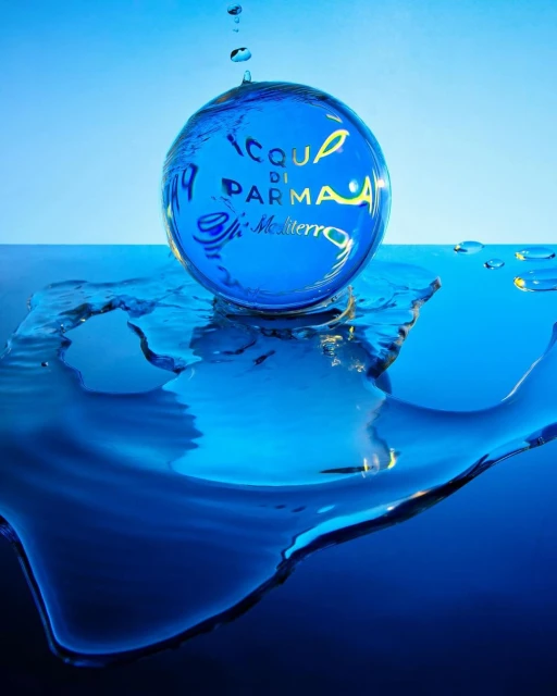 Acqua di Parma bottle captured in a spherical water drop, featuring blue liquid and background with clear brand labeling.