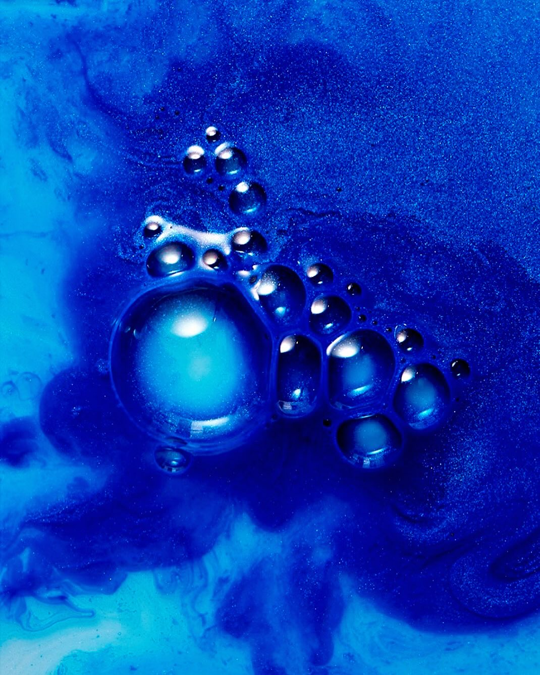 Abstract close-up of vibrant blue liquid with tiny bubbles and swirling patterns, creating a textured and dynamic visual experience.